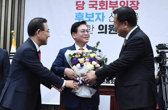 국민의힘 정우택 의원이 25일 국회에서 열린 의원총회에서 국회부의장 후보자로 선출된 뒤 정진석 비상대책위원장과 주호영 원내대표로부터 꽃다발을 받고 있다. <국회사진기자단>